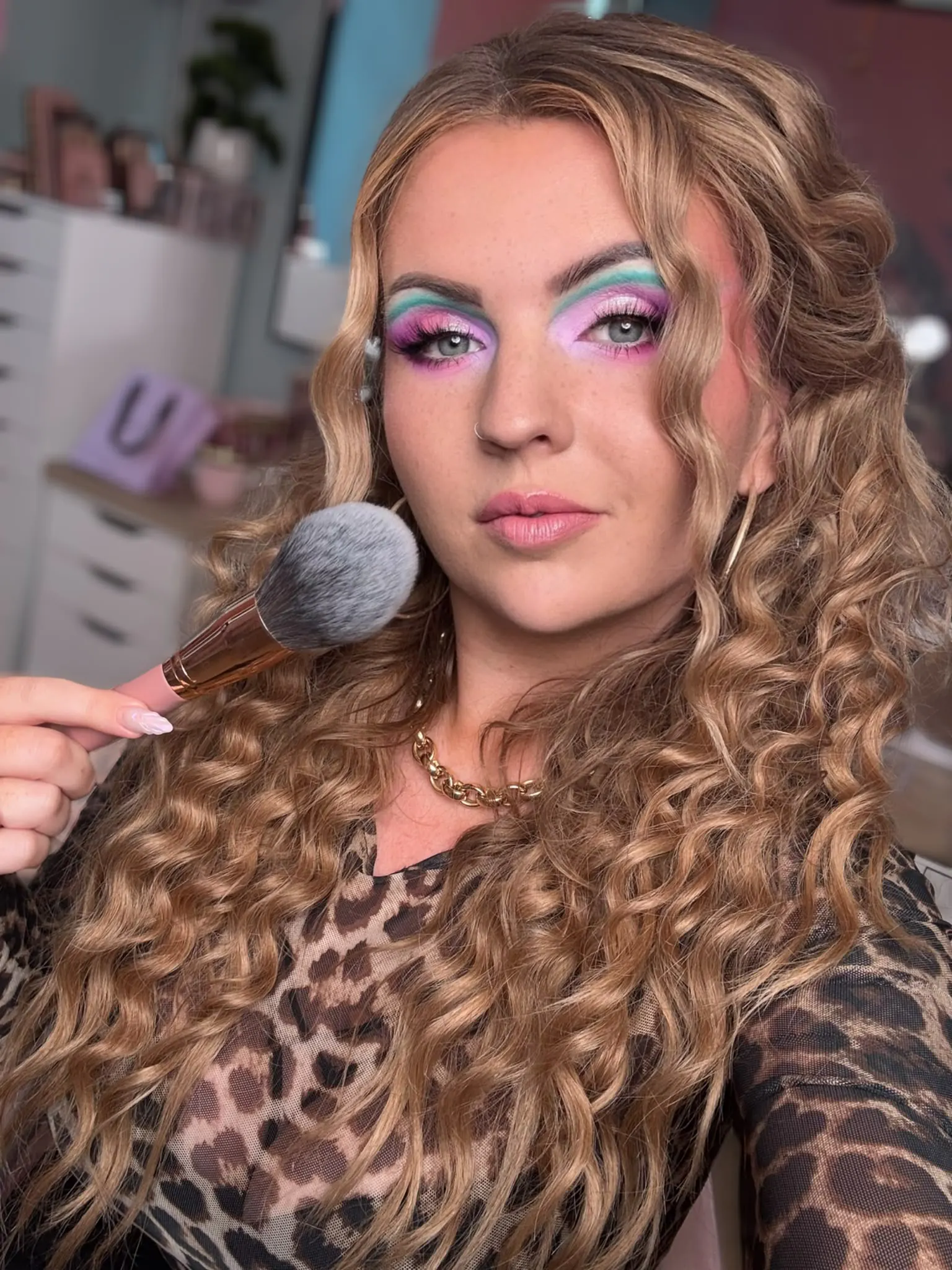 Nathalia in ihrem Studio, pastellfarbenes Augen-Make-up in Rosa und Türkis, Make-up-Pinsel in der Hand